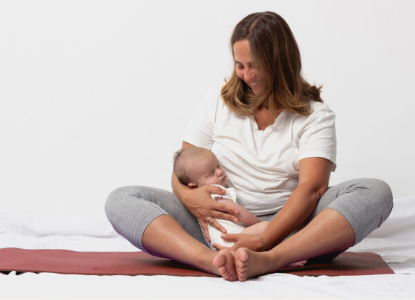 Happy mama holding a baby on a yoga mat